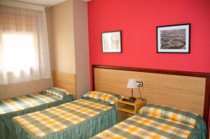 Habitación de hotel con 2 camas y paredes rojas en Habitacions Aurora, en Sant Pau de Segúries