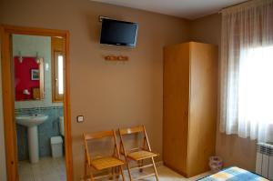a bathroom with two chairs and a tv on the wall at Habitacions Aurora in Sant Pau de Segúries