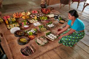 a woman sitting on the floor in front of a table of food at Amuna Ayurveda and Wellness Retreat in Sigiriya