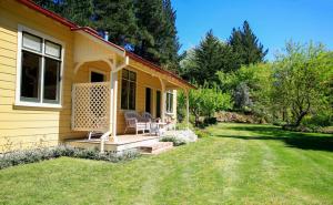 una casa amarilla con 2 sillas en un porche en Leader Valley Cottage - A Tranquil Retreat For Two, en Mendip Hills