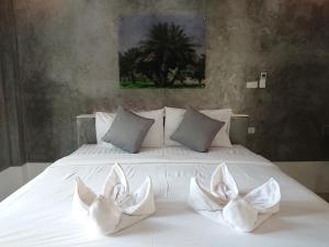 Una cama blanca con dos almohadas blancas. en Lopburi Palm Resort en Lop Buri