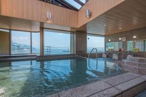 a large swimming pool in a building with windows at Hotel Sunmi Club in Atami