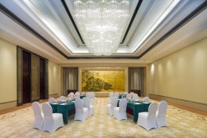 um quarto com mesas e cadeiras brancas e um lustre em Pan Pacific Serviced Suites Ningbo em Ningbo