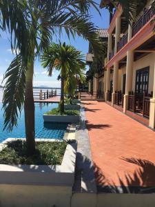 a resort with palm trees and a swimming pool at Pon Arena Hotel in Muang Không