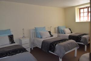 een kamer met drie bedden en een raam bij Hoog 109 High accommodation in Mosselbaai