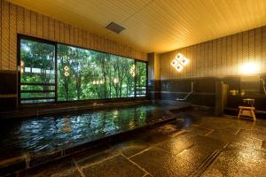 una piscina en un edificio con una ventana grande en TKP Lectore Atami Koarashi, en Atami