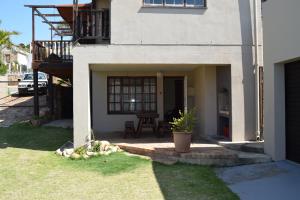 een huis met een patio en een tafel in een tuin bij Hoog 109 High accommodation in Mosselbaai
