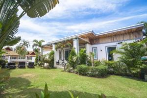 a white house with a yard with grass and trees at VILLA CHELONI 2 BEDROOMS in Kamala Beach