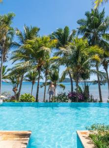 a man standing in a swimming pool next to the beach at Vanila Hotel & Spa in Ambaro