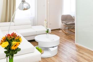 a white living room with a white couch and flowers at Convenience & Chic by the Basilica in Budapest