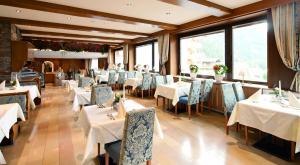 a restaurant with white tables and chairs and windows at Hotel Eberl in Finkenberg