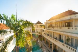 a view of a building with a palm tree at Bali Court Hotel & Apartment in Legian