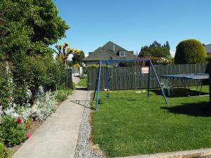 a yard with a swing set in the grass at Andorra Motel in Geraldine