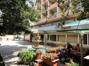 Diana 3 Hotel في صوفيا: يجلس شخصان على الطاولات أمام مبنى به نافورة