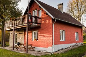 ein rotes Backsteinhaus mit einem Balkon und einem Picknicktisch in der Unterkunft Chalupa Na Žofíně in Horní Podluží