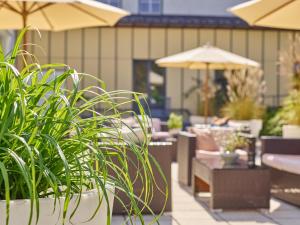 eine Terrasse mit Stühlen, Sonnenschirmen und Pflanzen in der Unterkunft Fit Vital Aktiv Hotel DAS LUDWIG in Bad Griesbach