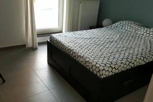 ein Schlafzimmer mit einem Bett in einem Zimmer mit einem Fenster in der Unterkunft Residentie Koen in Ostende