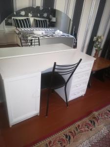 a white desk with a chair next to a bed at Nikoloz Guesthouse in Stepantsminda