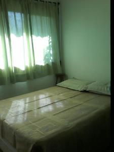 ein großes Bett in einem Schlafzimmer mit Fenster in der Unterkunft Condominio Village Camburi in Camburi