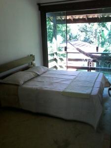 ein großes Bett in einem Schlafzimmer mit großem Fenster in der Unterkunft Condominio Village Camburi in Camburi