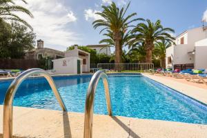 a swimming pool with palm trees and a resort at Apartamento Las Palmeras in Cala Blanca