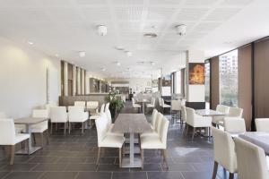 une salle à manger avec des tables et des chaises blanches dans l'établissement Odalys City Lyon Confluence, à Lyon