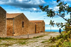 uma mulher a andar em frente a um edifício de tijolos em Agriturismo Case Tabarani em Collesano