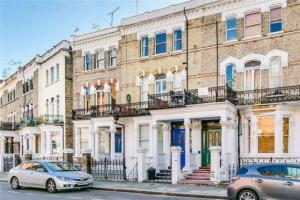 two cars parked in front of a large brick building at West Kensington 2Bed Flat in London