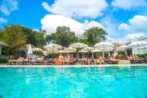 a pool with people sitting in chairs and umbrellas at The Hive Hotel - SHA Plus in Lamai