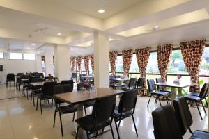a dining room with tables and chairs and windows at Highland Resort in Lonavala