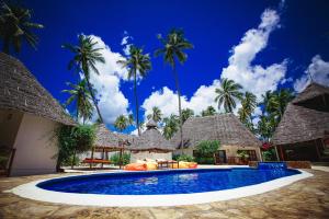 a resort swimming pool with palm trees in the background at Sea View Lodge Boutique Hotel in Jambiani