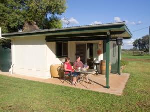 un hombre y una mujer sentados en una mesa fuera de un cobertizo en Charleville Bush Cottage, en Charleville