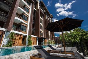 an umbrella and chairs next to a swimming pool at Natee The Riverfront Hotel Kanchanaburi in Kanchanaburi