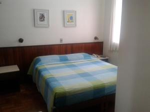 Hotel São Bento في بيلو هوريزونتي: غرفة نوم بسرير وبطانية زرقاء وصفراء