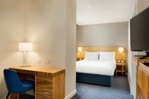 a hotel room with a bed and a desk at Ramada Hotel & Suites by Wyndham Coventry in Coventry