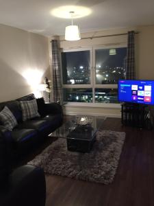 a living room with a black couch and a television at AB11 Apartments - Portland Street in Aberdeen