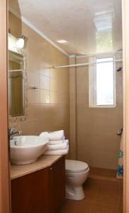 uma casa de banho com um lavatório, um WC e um espelho. em Akrogiali em Míloi