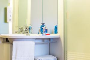 a bathroom sink with a toothbrush holder and toothpaste dispenser at ibis budget Leuven Centrum in Leuven