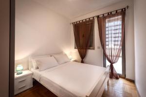 a bedroom with a white bed and a window at Apartments Montreal in Budva