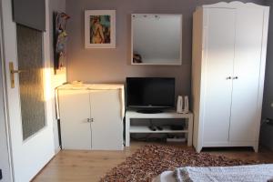 uma sala de estar com televisão e armários brancos em Zimmer David em Colônia