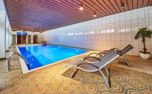 a swimming pool in a building with a chair next to it at Appartement Ski & Bike in Saalbach Hinterglemm