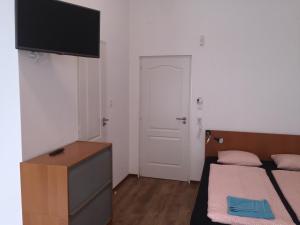 a bedroom with two beds and a tv on the wall at Omega Guesthouse Budapest in Budapest