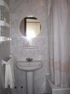 Baño blanco con lavabo y espejo en Pensión K-Hito en Santiago de la Ribera