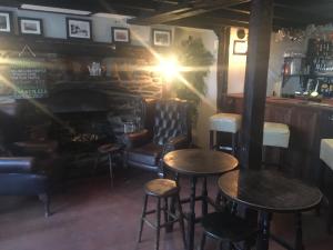 a bar with two tables and chairs and a fireplace at Crown Inn in Rhayader