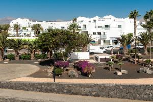 a park with flowers and trees in front of a building at Hotel Lanzarote Village in Puerto del Carmen