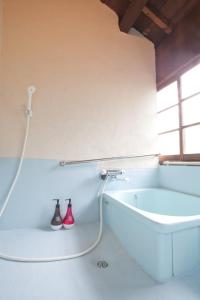 a white bathroom with a hose attached to a wall at Guest House Kura in Suzaka