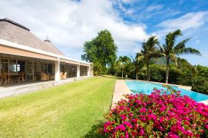 an exterior view of a house with a swimming pool and flowers at Le Petit Morne Lodge in Le Morne