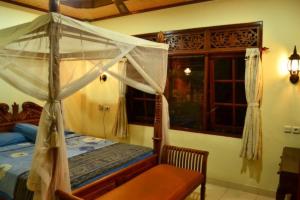 a bedroom with a canopy bed and a window at Nyoman Murjana Homestay in Ubud