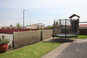 a swing set in a backyard with a brick wall at Anandi Guesthouse Swakopmund in Swakopmund