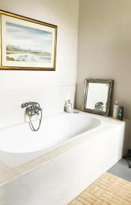 een wit bad in een kamer met een spiegel bij Kimi's Cottage in Simondium